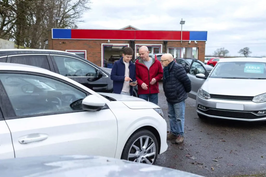 Three people in a car lot