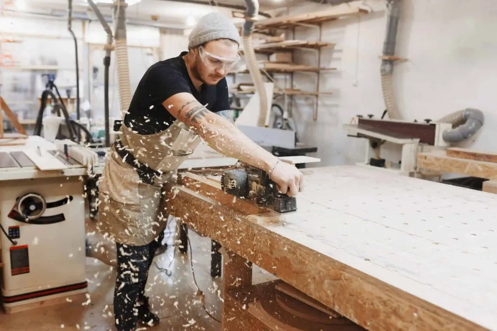 Man using planer on wood in a shop