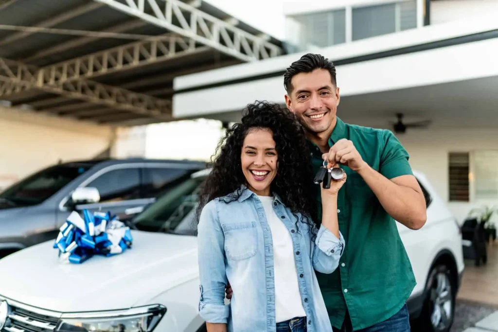 A couple in front of a new car with a bow on it